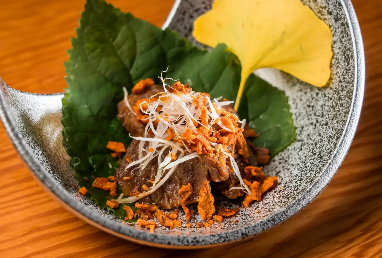 Japanese beef appetizer topped with shredded scallions, served in a ceramic bowl
