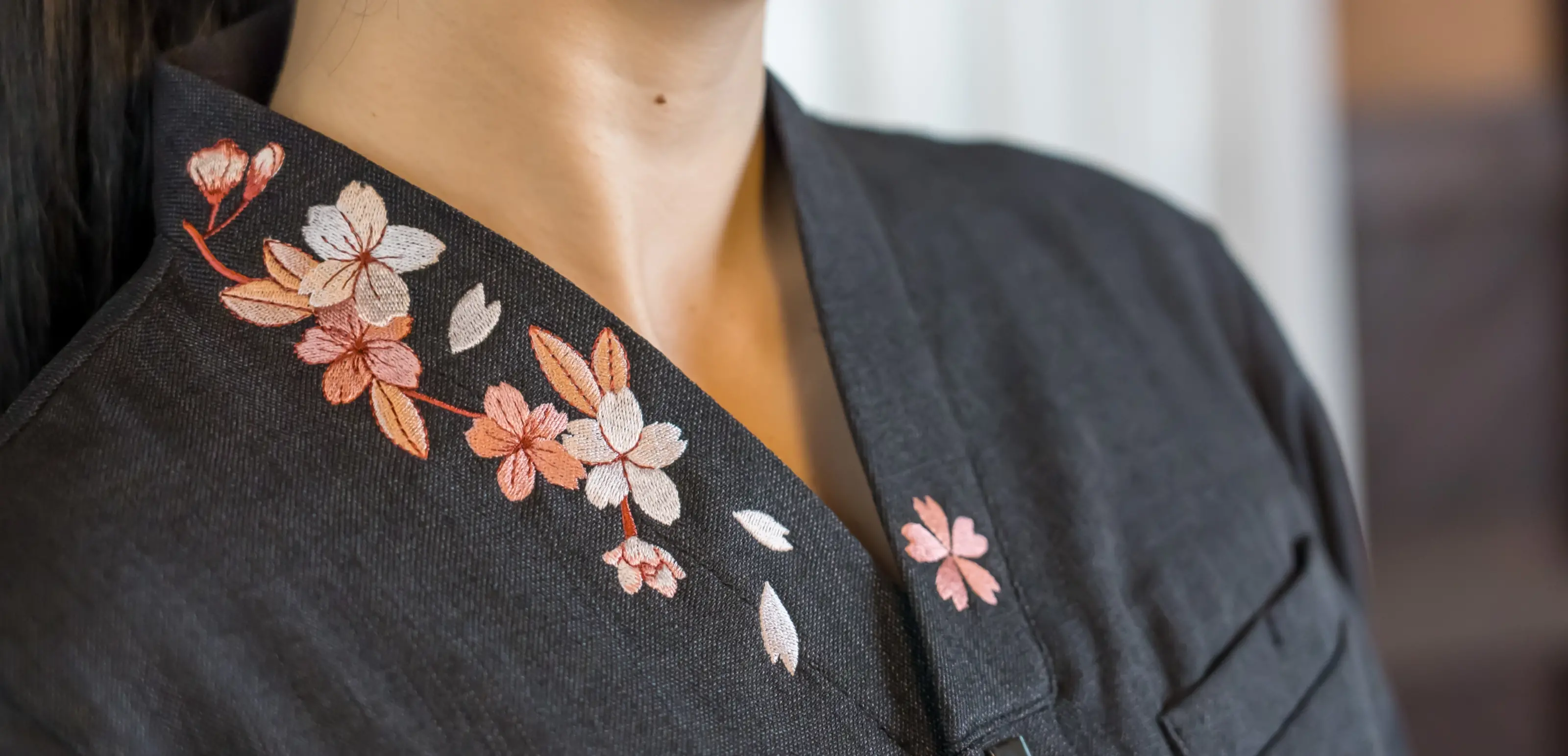 Hospitality staff wearing a black uniform shirt with a Mount Fuji motif, welcoming guests